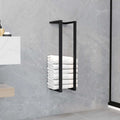 Black iron towel rack holding rolled towels in bathroom